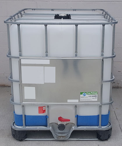 used ibc tote on concrete with white cinderblock wall behind