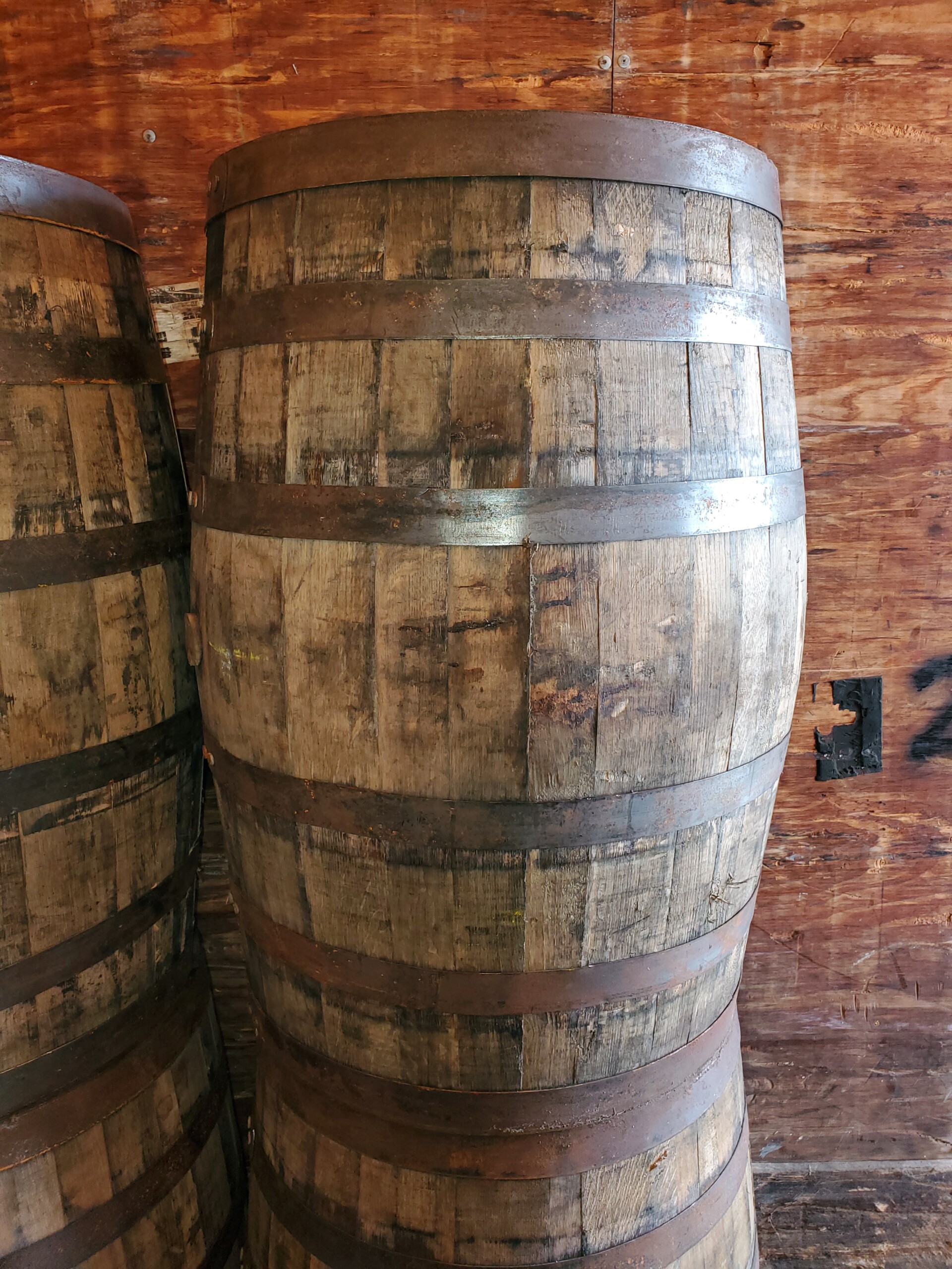 maker’s mark wooden barrel with wooden barrels in background