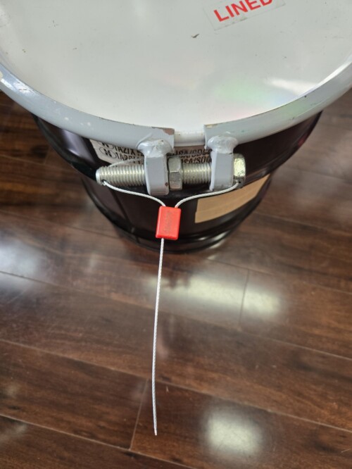seal in use on security bolt on metal drum sitting on wood floor